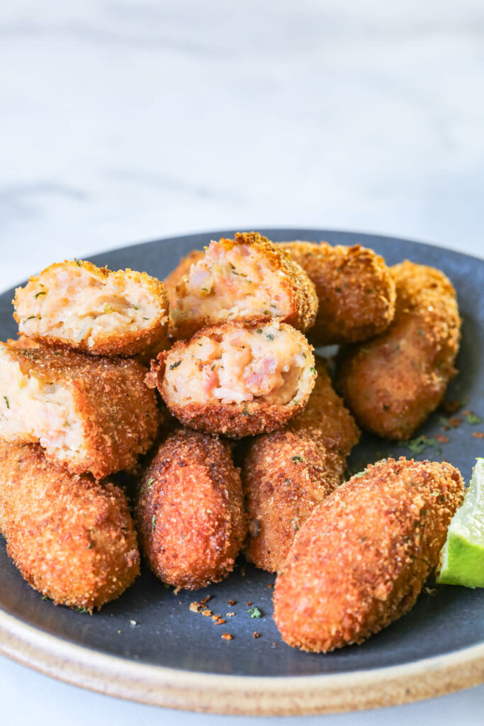 Open croquette on a pile of croquettes on a gray plate.