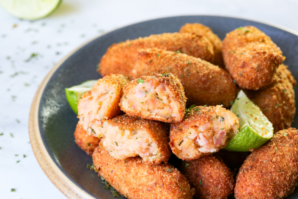 a pile of croquettes on a gray plate with lime wedges