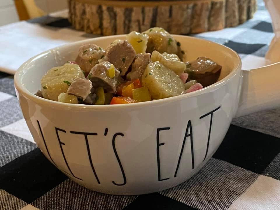 a let's eat bowl filled with gizzards and bananas over a white and black cloth