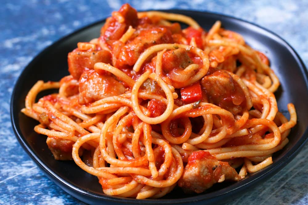 pasta with pork chops on a black plate