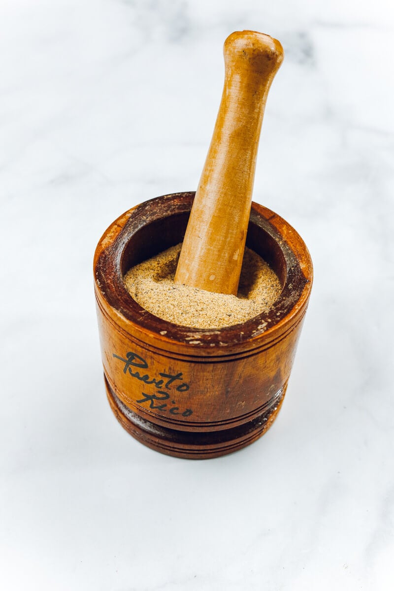 A wooden mortar and pestle filled with dry spices.