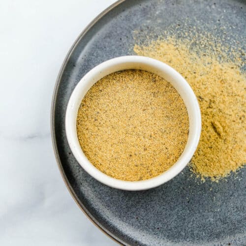 A small white ramekin filled with adobo seasoning over a gray plate.