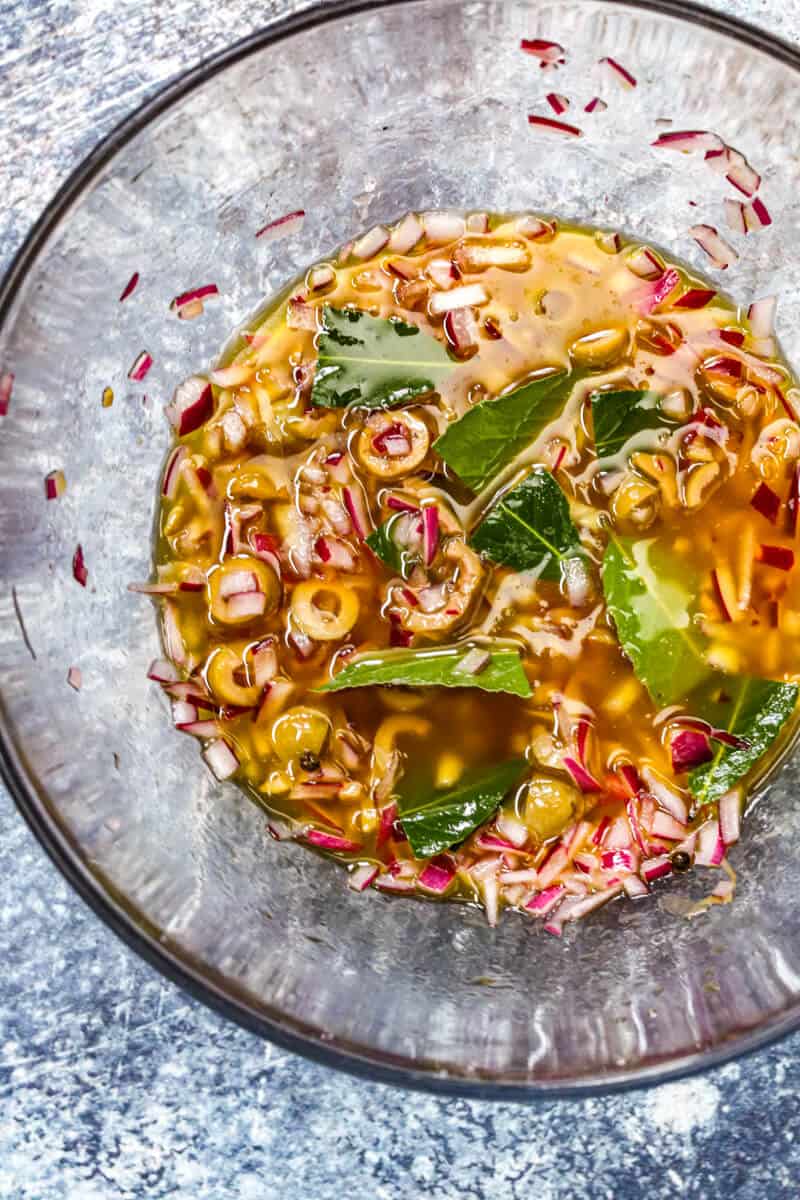 Sauce for escabache de mollejas or Puerto Rican pickled green bananas in a glass bowl.