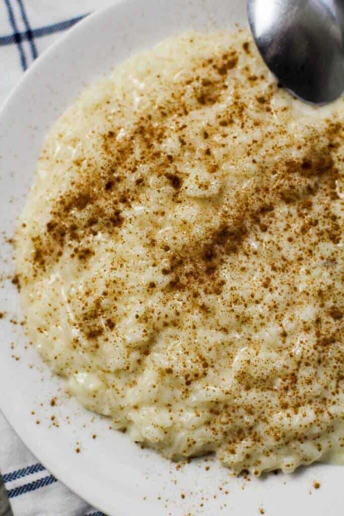 Arroz con leche de dulce (rice pudding) topped with ground cinnamon on a white plate.