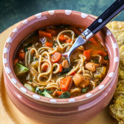 A bowl of noodle soup, known as sopa de fideo is filled with veggies, chicken, and noodles in a rich broth.