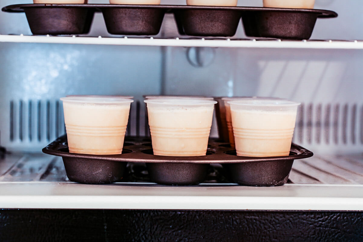 An open freezer with two muffin trays that are lined with frozen limbers.
