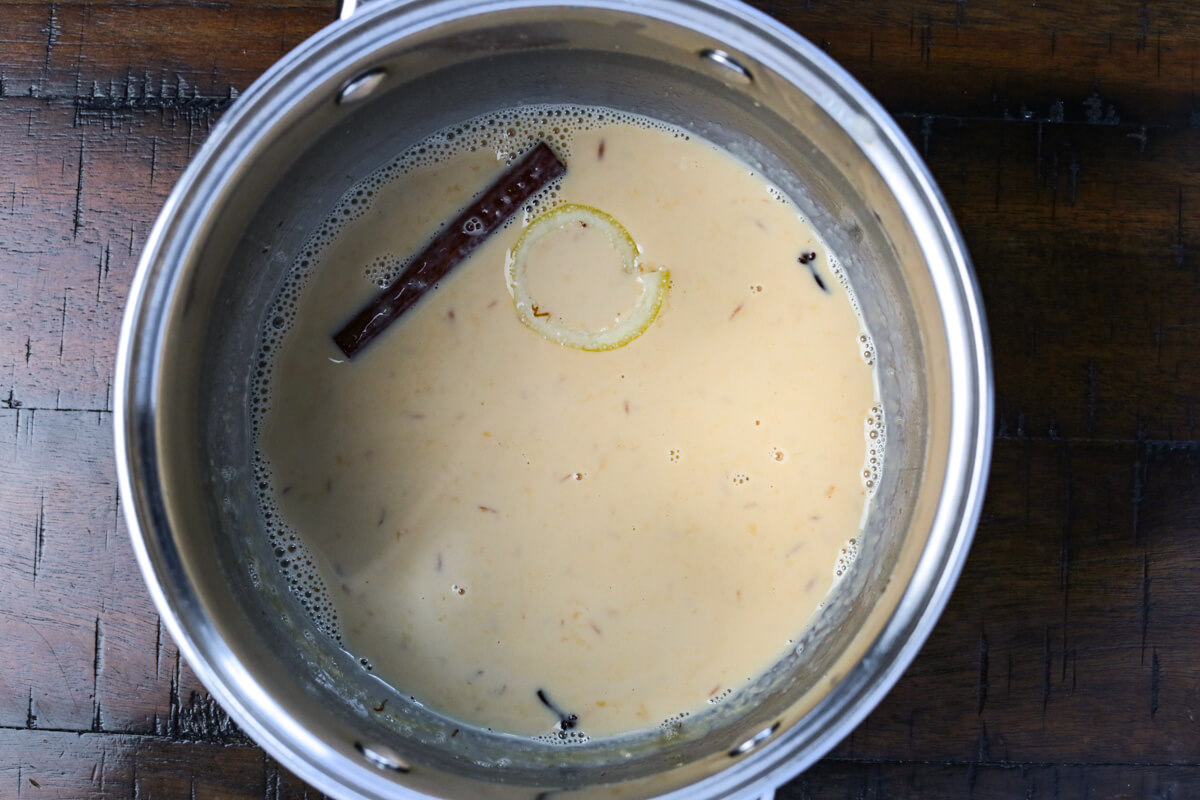 A small metal pot is filled with evaporated milk that's infused with spices and a lemon rind.
