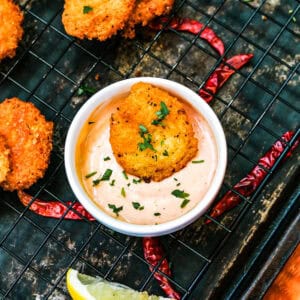 Cuban malanga fritters in a dip on a wire rack