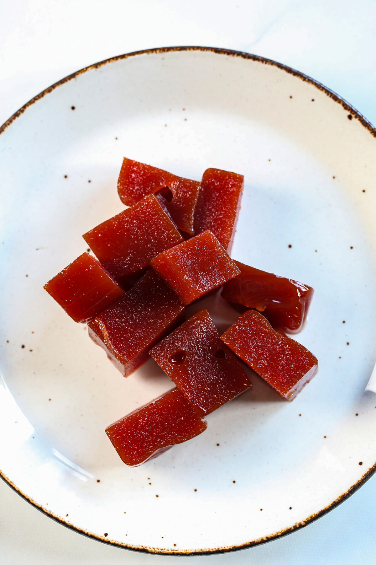 Close up shot of cubed guava paste on a white speckled plate.