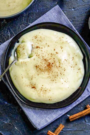 Natilla (Maizena) with cinnamon is on a black plate with a blue background