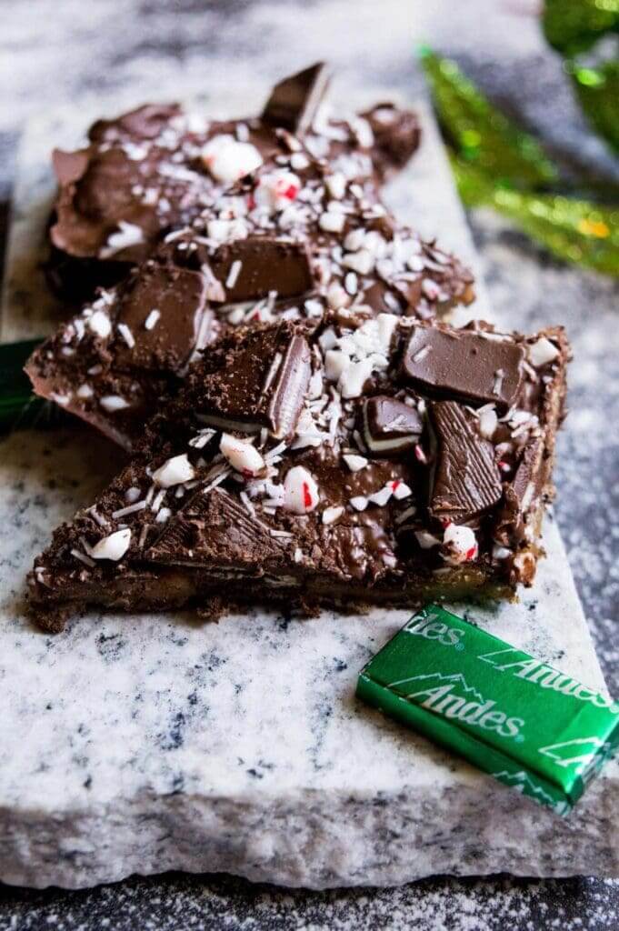 Close up shot of chocolate toffee topped with crushed peppermint on a granite slab