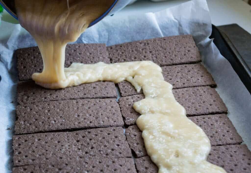Fresh toffee being poured over chocolate graham crackers