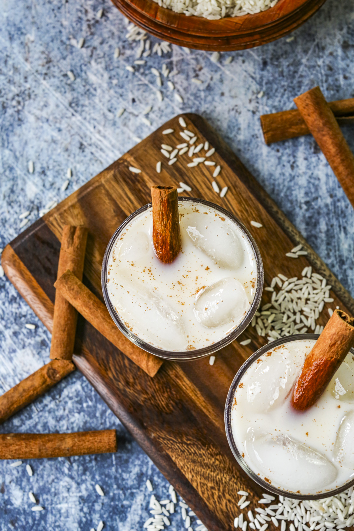 Overhead image of horchata in a glass cup full of ice with a blue background.