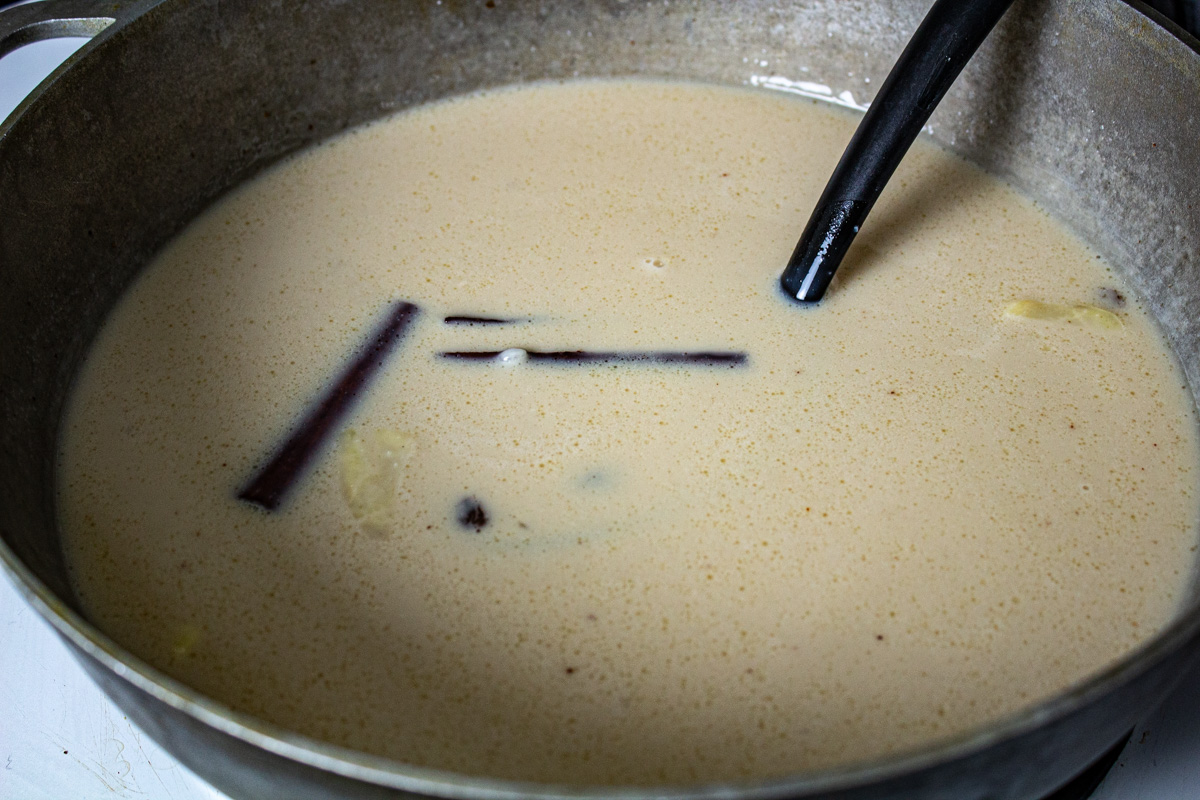 Caldero filled with milk and cinnamon sticks that are floating on top.