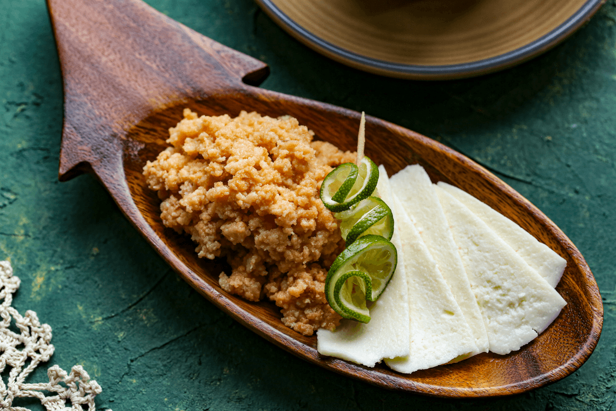 A close up of a serving of dulce de leche cortada with sliced queso fresco on a wooden serving dish.