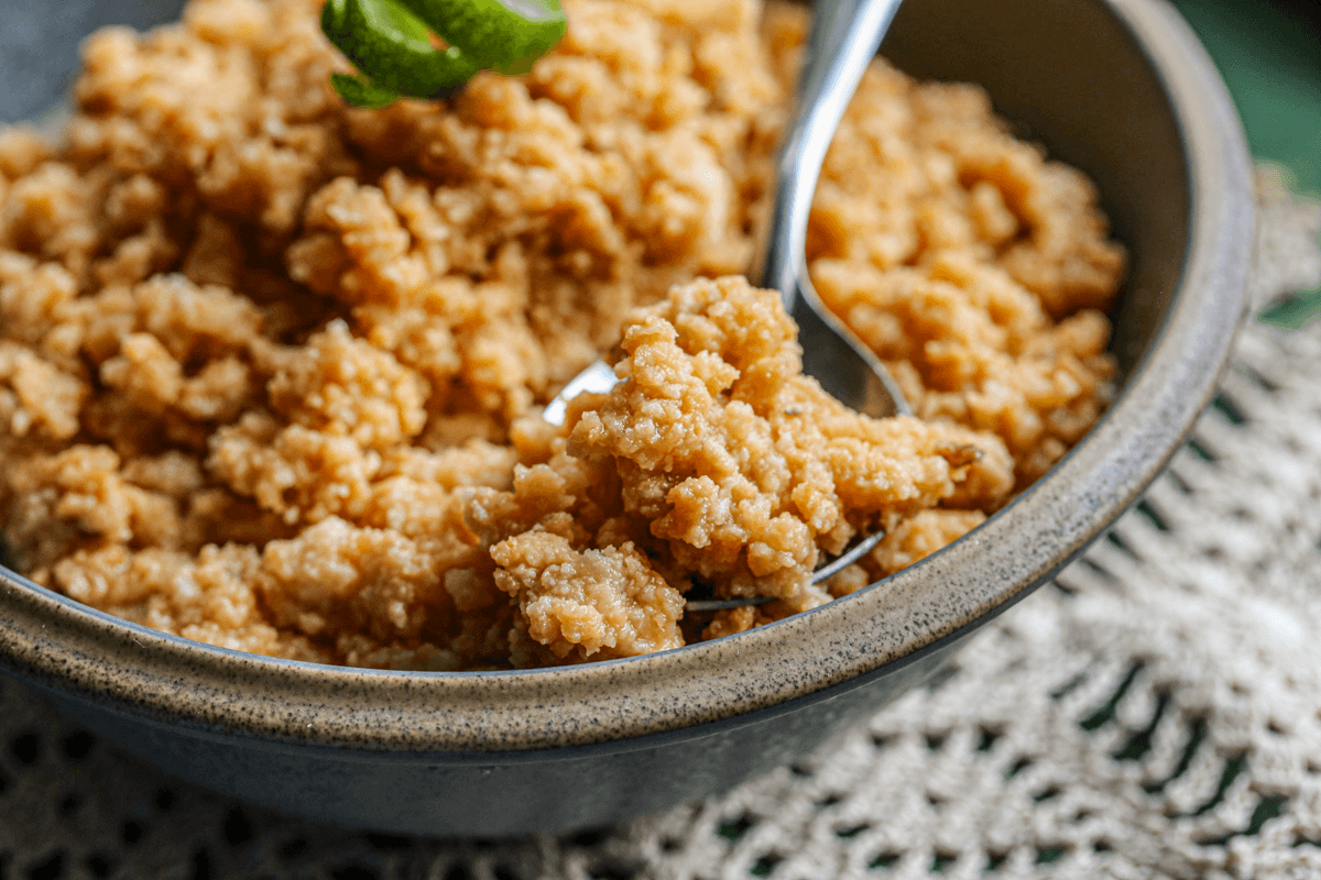 Close up shot of sweet sour milk dessert on a metal spoon in a gray bowl.