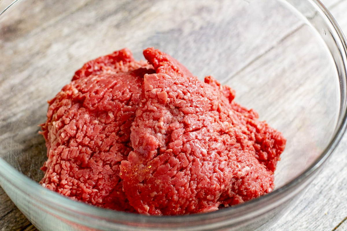 Raw cubed steak in a glass bowl.