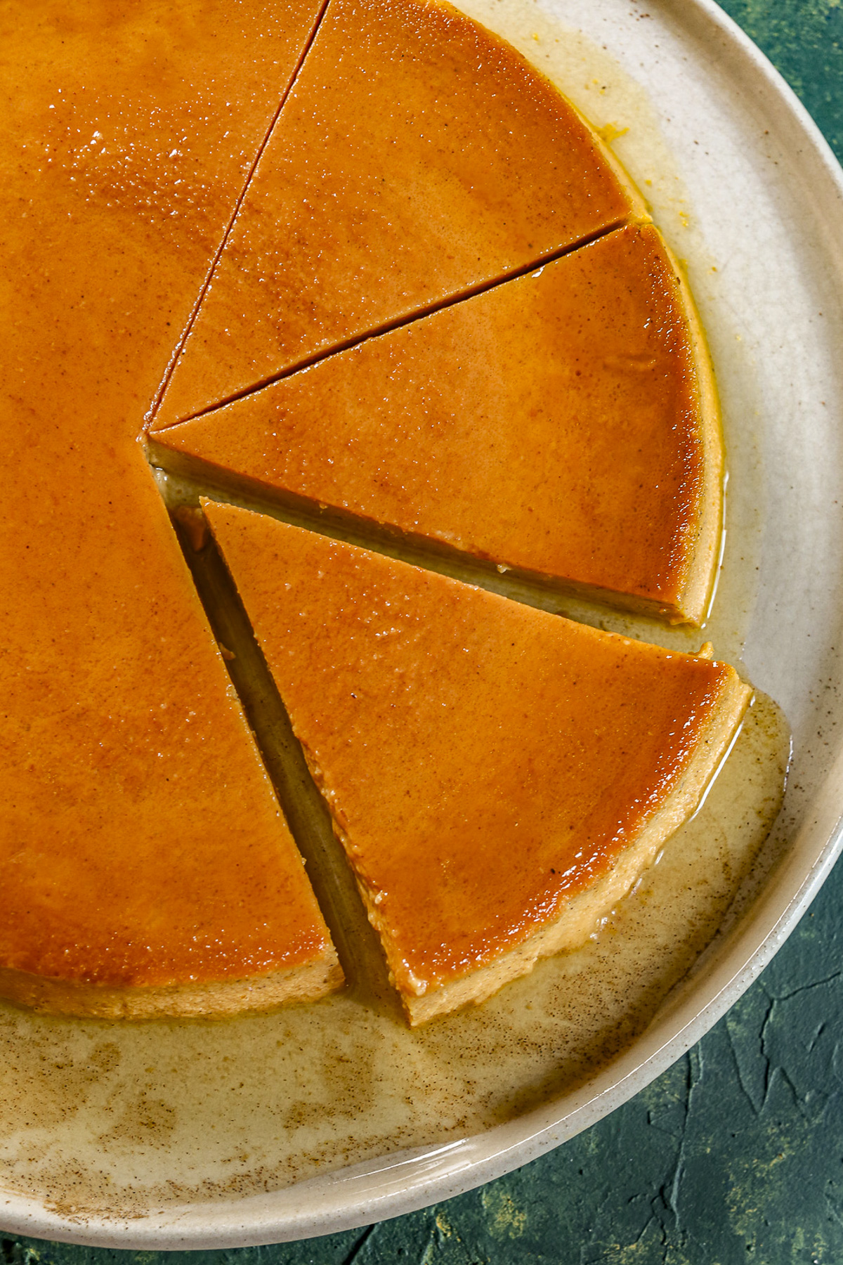 A white rimmed plate has sliced orange hue flan on it.